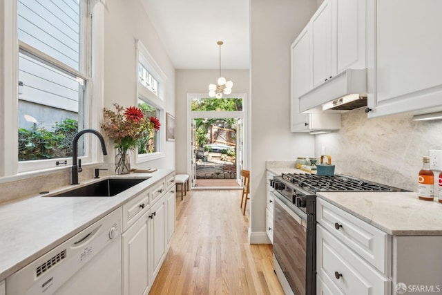 kitchen featuring decorative backsplash, range with gas stovetop, white dishwasher, under cabinet range hood, and a sink