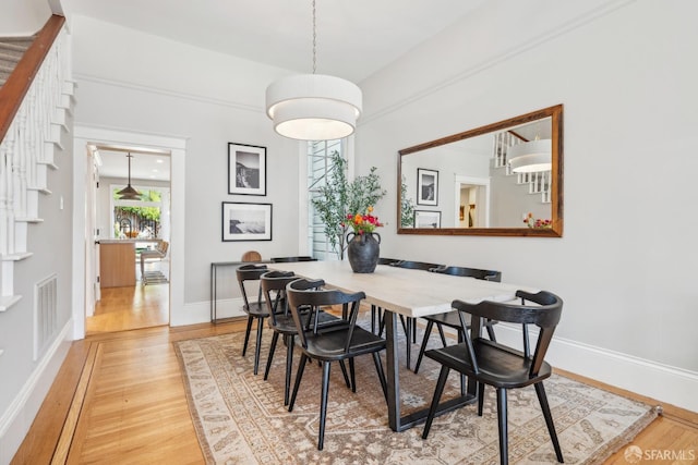 dining area featuring visible vents, light wood-style flooring, baseboards, and stairs