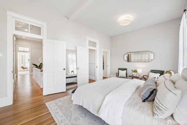 bedroom featuring light wood-type flooring and beam ceiling