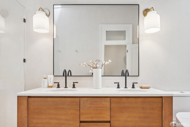 bathroom with a sink, toilet, and double vanity