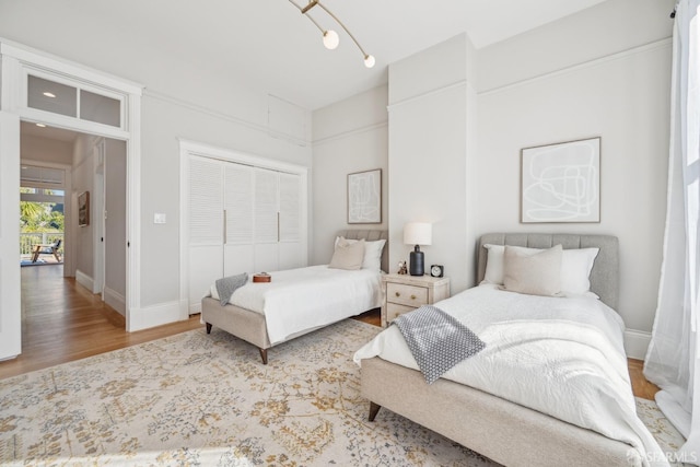 bedroom with a closet, wood finished floors, and baseboards