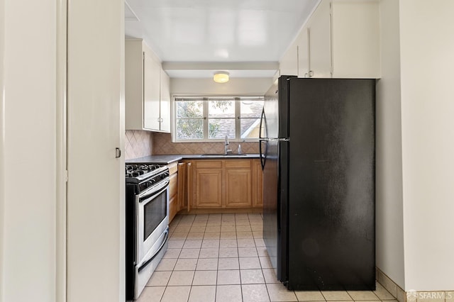 kitchen with gas stove, sink, tasteful backsplash, black refrigerator, and light tile patterned floors