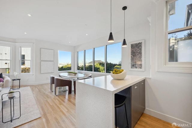 kitchen featuring hanging light fixtures, kitchen peninsula, and light wood-type flooring