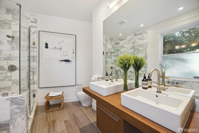 bathroom featuring wood-type flooring, toilet, a shower with door, and vanity