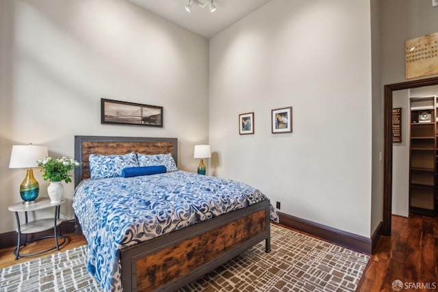 bedroom with wood finished floors, baseboards, and rail lighting