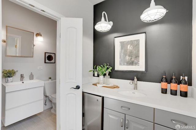 bathroom with toilet, two vanities, and a sink