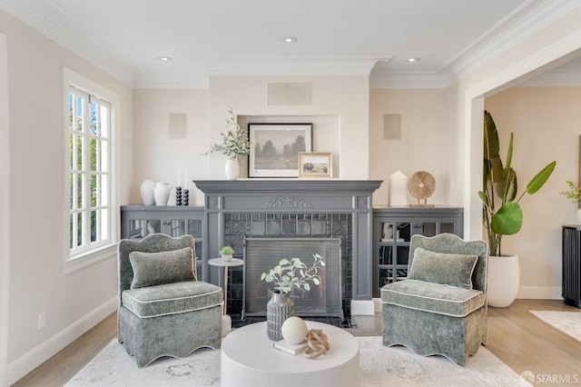 living area with wood finished floors, crown molding, and a tile fireplace