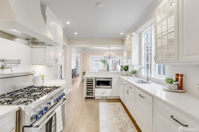 kitchen with glass insert cabinets, premium range hood, beverage cooler, appliances with stainless steel finishes, and a sink