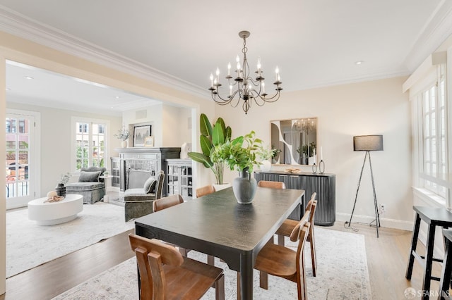 dining space featuring crown molding, a fireplace, light wood-type flooring, and baseboards