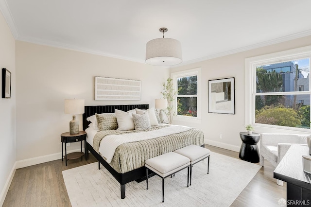 bedroom with baseboards, multiple windows, wood finished floors, and crown molding