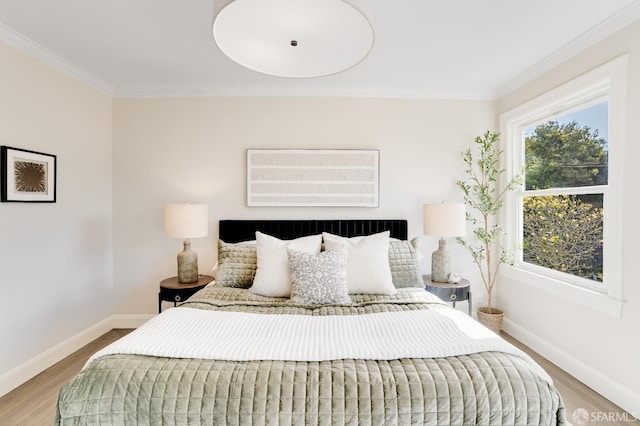 bedroom with crown molding, baseboards, and wood finished floors