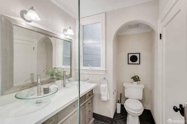 full bath with a sink, double vanity, toilet, and ornamental molding