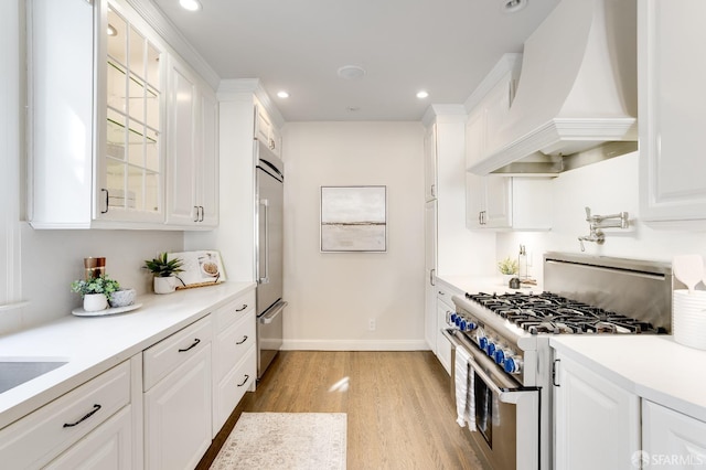 kitchen featuring light wood-style flooring, custom range hood, glass insert cabinets, white cabinetry, and high quality appliances