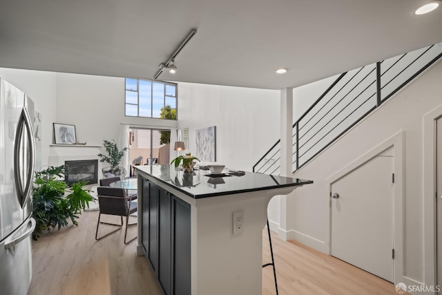 39 Boardman Pl Unit 105, San Francisco, CA 94103 - kitchen with freestanding refrigerator, a kitchen breakfast bar, light wood-style floors, rail lighting, and a center island