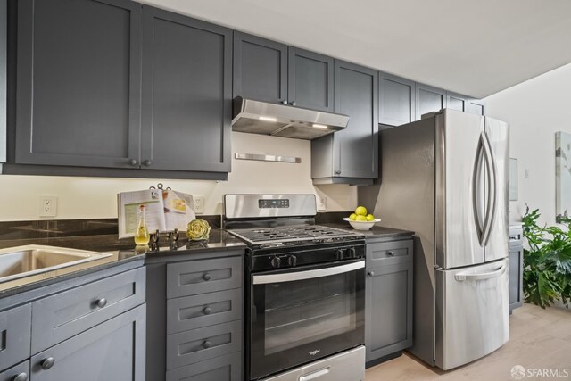 39 Boardman Pl Unit 105, San Francisco, CA 94103 - kitchen featuring stainless steel appliances, under cabinet range hood, dark countertops, and light wood-style flooring
