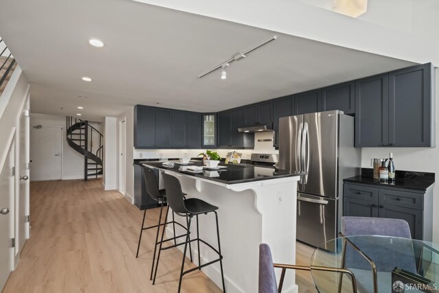 39 Boardman Pl Unit 105, San Francisco, CA 94103 - kitchen featuring stainless steel appliances, dark countertops, a breakfast bar, light wood-type flooring, and recessed lighting