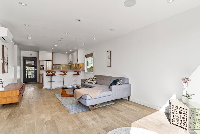 living room featuring a wall mounted air conditioner and light hardwood / wood-style flooring