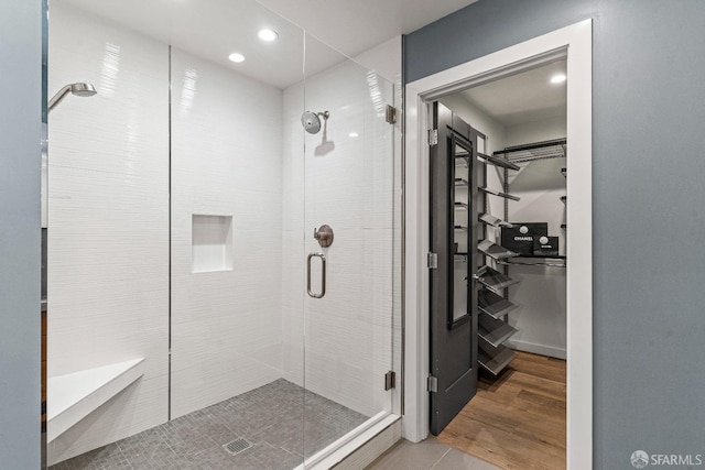 bathroom featuring a shower with shower door and hardwood / wood-style floors