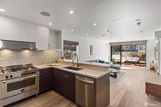 kitchen with wall chimney exhaust hood, sink, white cabinetry, and stainless steel appliances