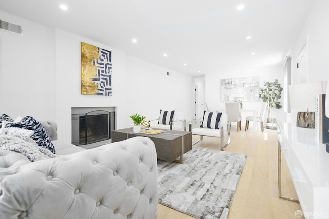 living room featuring a fireplace, recessed lighting, visible vents, and light wood finished floors