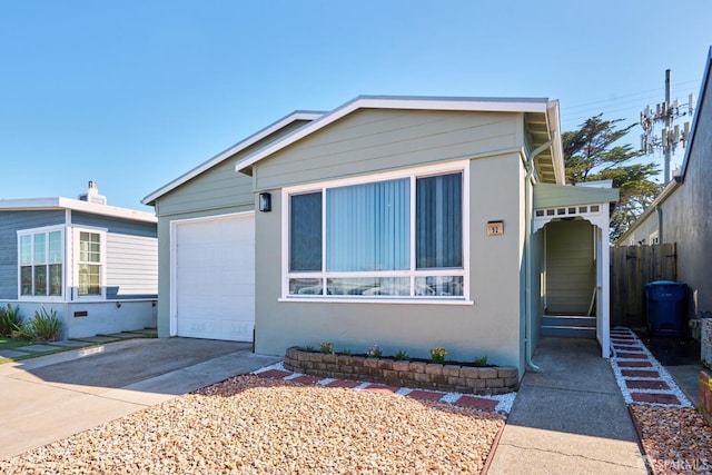 view of front of property featuring concrete driveway, an attached garage, and fence