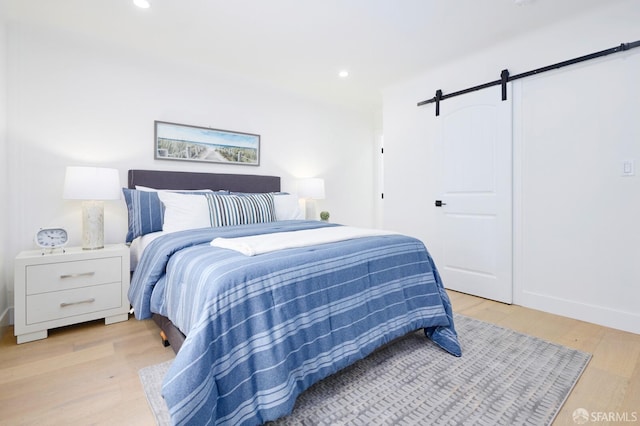 bedroom featuring a barn door, recessed lighting, and light wood-type flooring