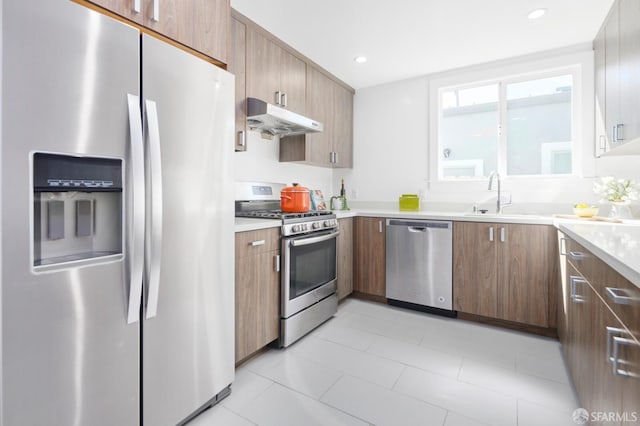 kitchen featuring under cabinet range hood, a sink, recessed lighting, appliances with stainless steel finishes, and light countertops