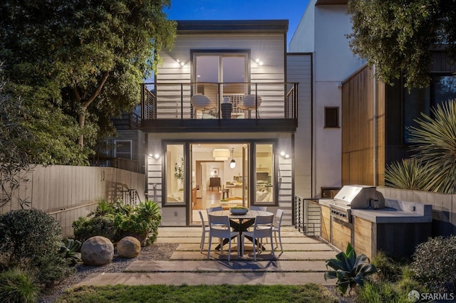 rear view of property with an outdoor kitchen, a patio, a balcony, and fence