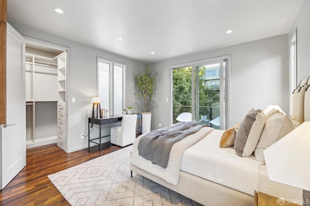 bedroom with a walk in closet, access to outside, wood finished floors, recessed lighting, and baseboards