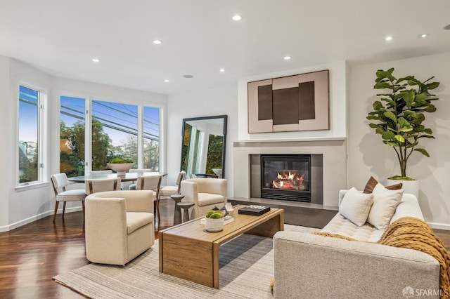 living room with a glass covered fireplace, recessed lighting, wood finished floors, and baseboards