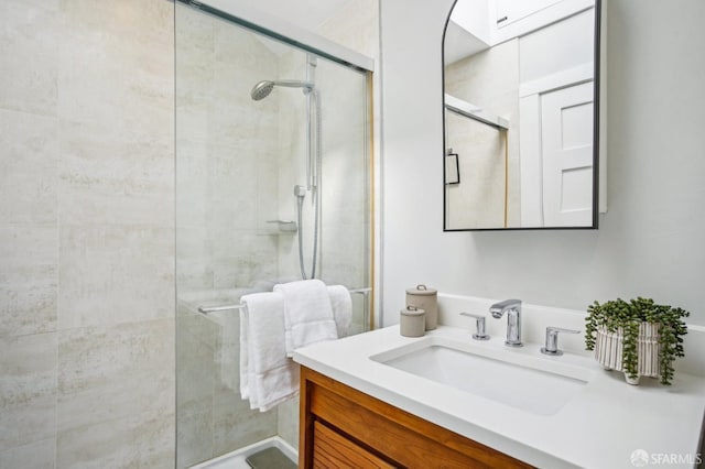 full bathroom with a tile shower and vanity