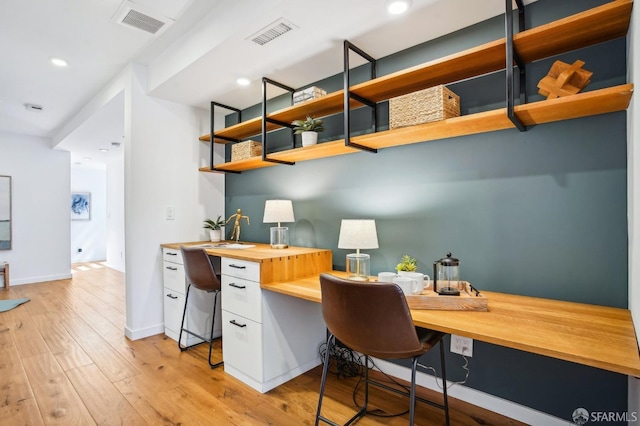 home office with visible vents, recessed lighting, built in study area, and light wood-style floors