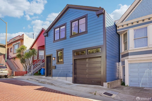 townhome / multi-family property with decorative driveway, a garage, and stairway