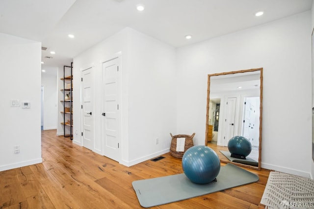 workout room with light wood-style flooring, recessed lighting, and baseboards