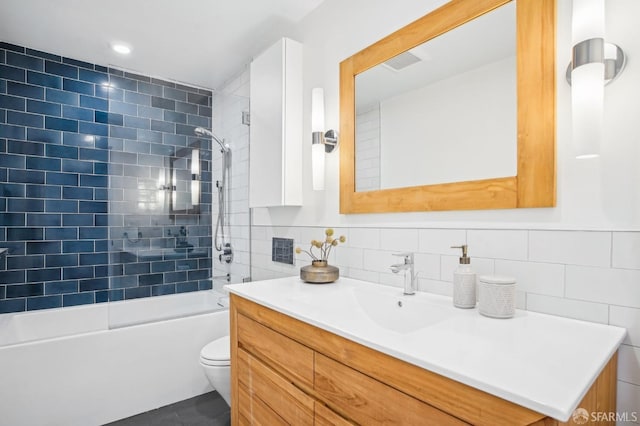 bathroom with vanity, tile walls, toilet, and shower / bathtub combination