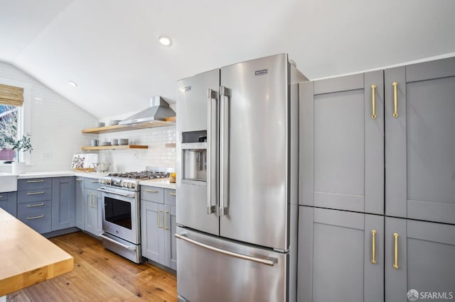 kitchen with gray cabinetry, open shelves, light wood-style floors, lofted ceiling, and high end appliances