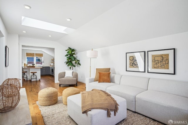 living room featuring recessed lighting, vaulted ceiling with skylight, and wood finished floors