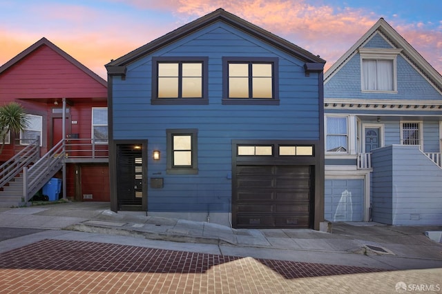 view of front facade featuring stairway, an attached garage, and driveway