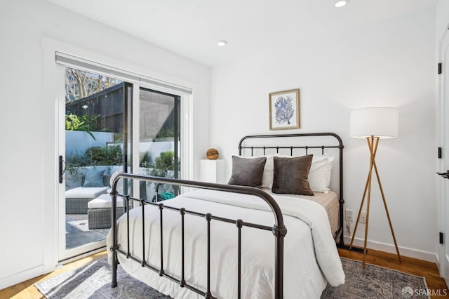 bedroom with access to outside, recessed lighting, wood finished floors, and baseboards