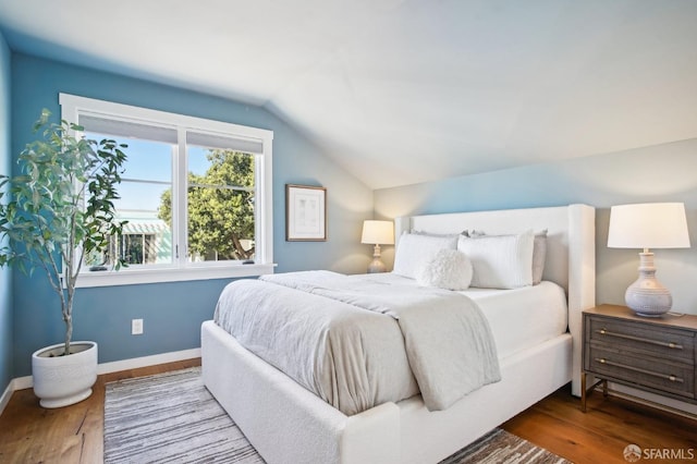 bedroom with baseboards, wood finished floors, and vaulted ceiling