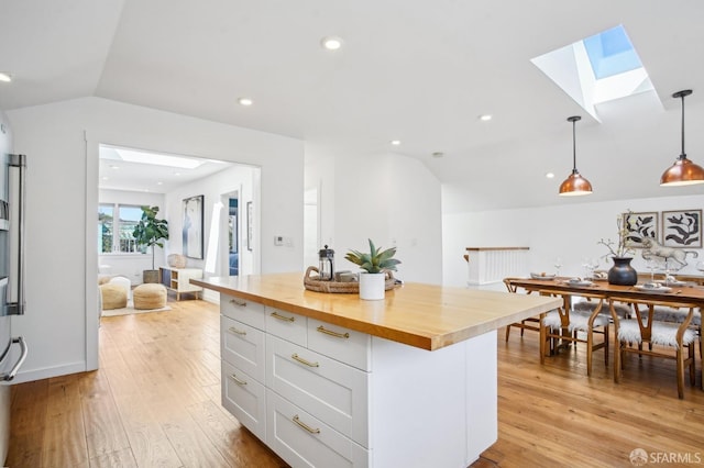 kitchen with recessed lighting, butcher block countertops, hanging light fixtures, lofted ceiling with skylight, and light wood-type flooring