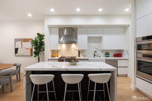1935 Greenwich St, San Francisco, CA 94123 - kitchen with double oven, white cabinets, wall chimney range hood, a center island, and modern cabinets