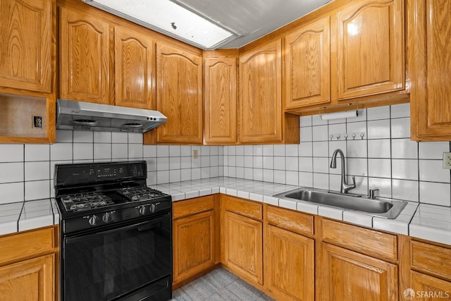 kitchen with black range with gas cooktop, sink, tile countertops, and exhaust hood