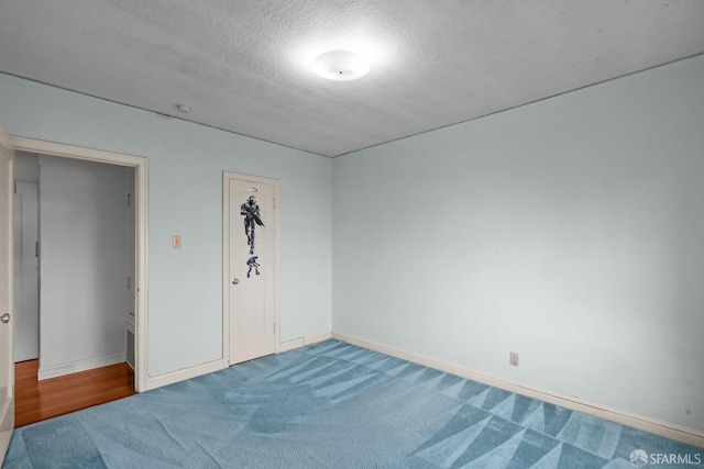 carpeted empty room featuring a textured ceiling