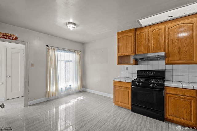 kitchen featuring decorative backsplash, tile counters, and black gas stove