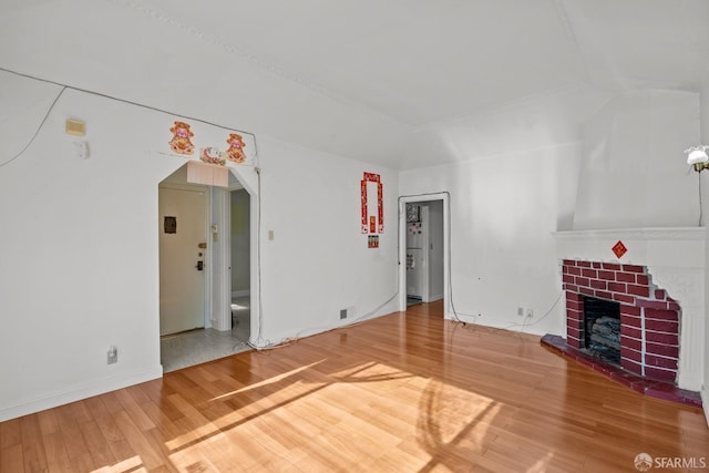 unfurnished living room featuring lofted ceiling, hardwood / wood-style floors, and a fireplace