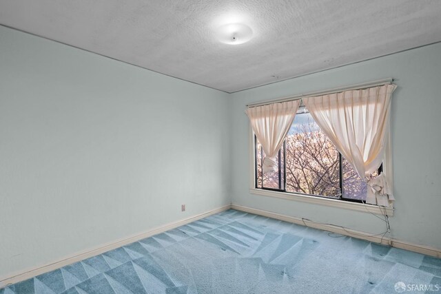 carpeted empty room with a textured ceiling