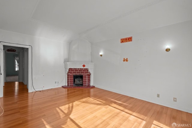 unfurnished living room with hardwood / wood-style floors and a brick fireplace