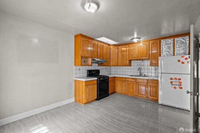 kitchen with tasteful backsplash, sink, white fridge, and black gas range oven