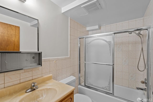 full bathroom with vanity, toilet, combined bath / shower with glass door, and tile walls